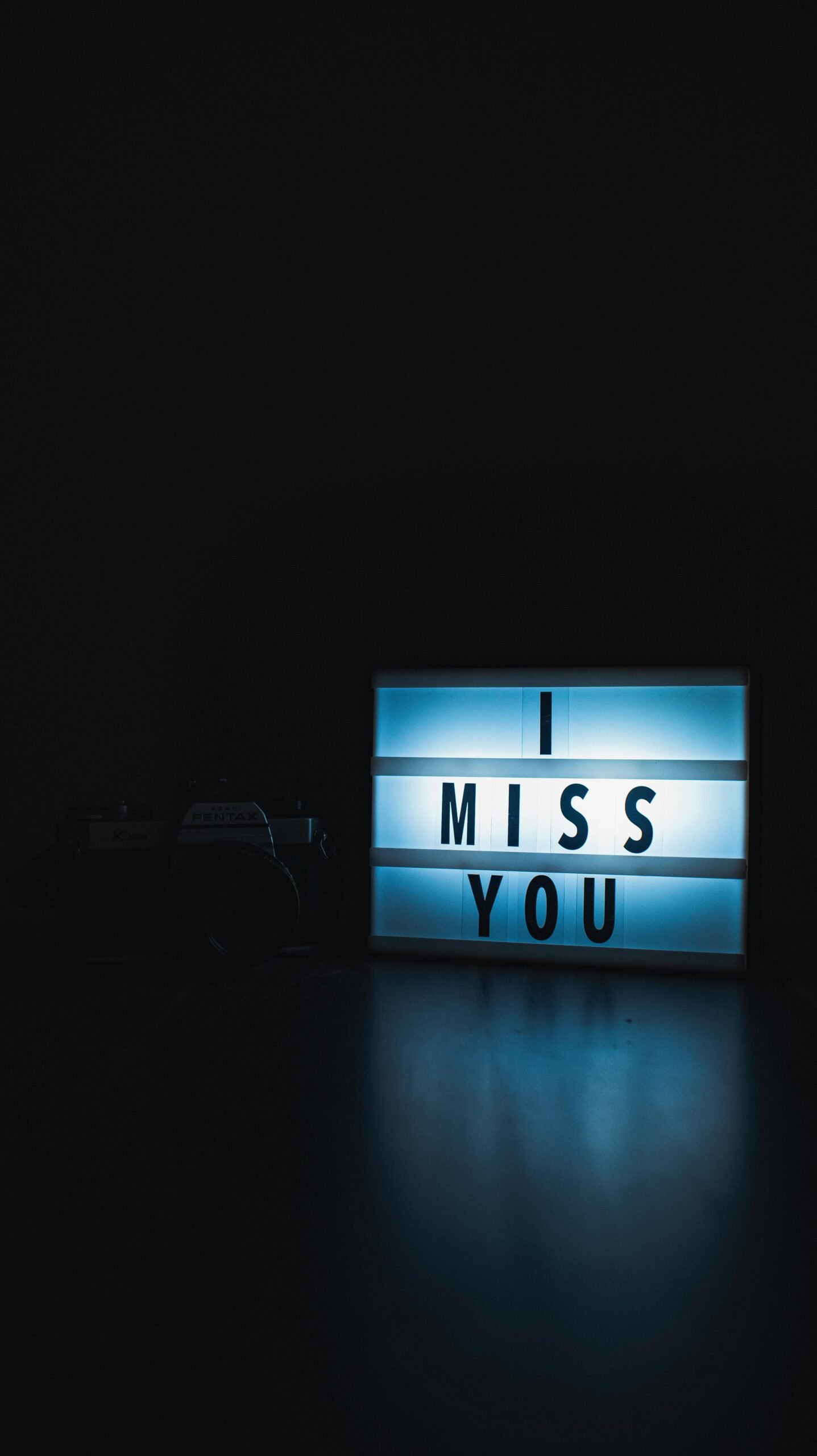 A glowing light box displaying 'I Miss You' in a dark setting, evoking emotion.